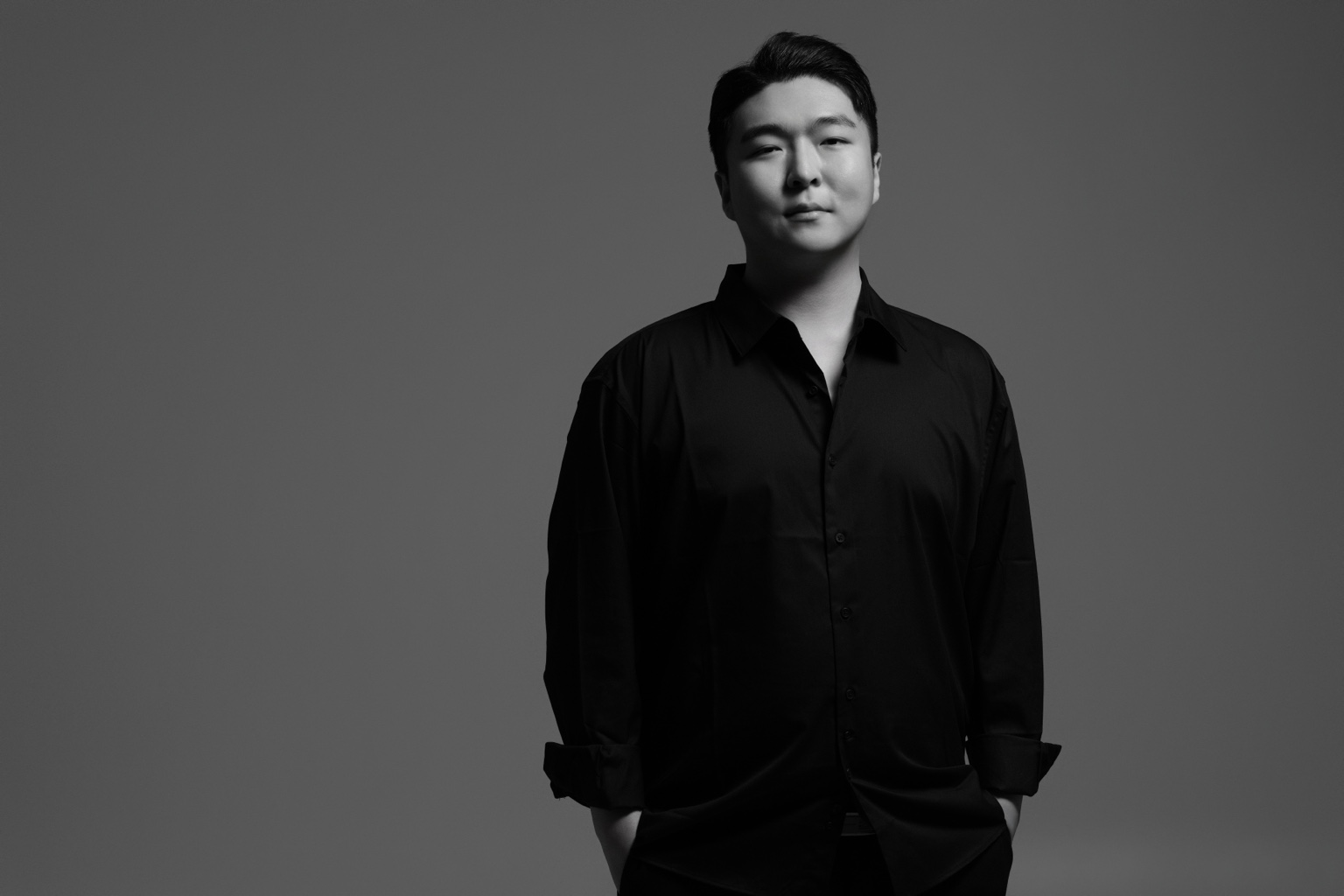 Stephano Park — black-and-white portrait in a black shirt, hands in pockets